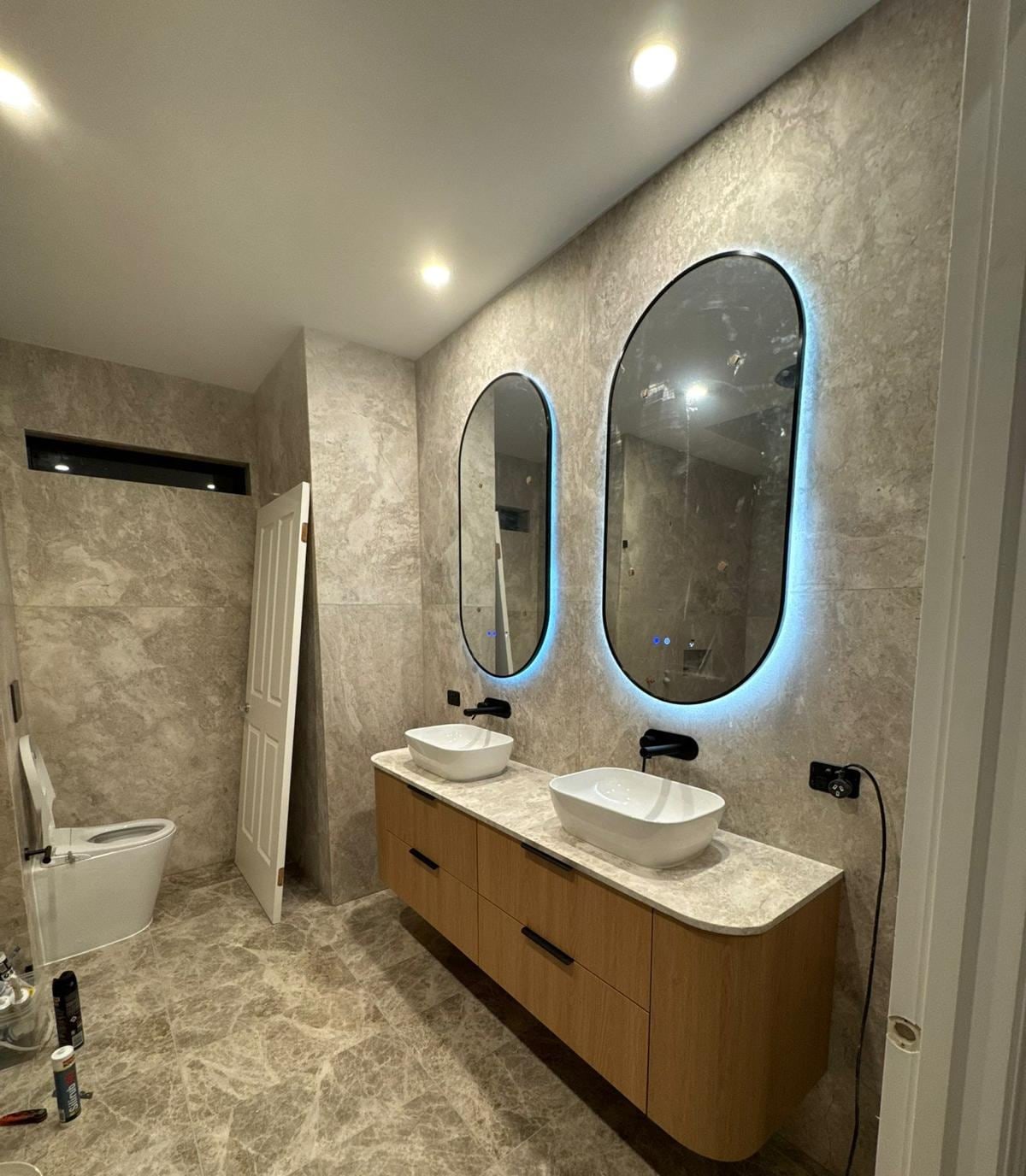 Renovated bathroom with double vanity and twin backlit mirrors
