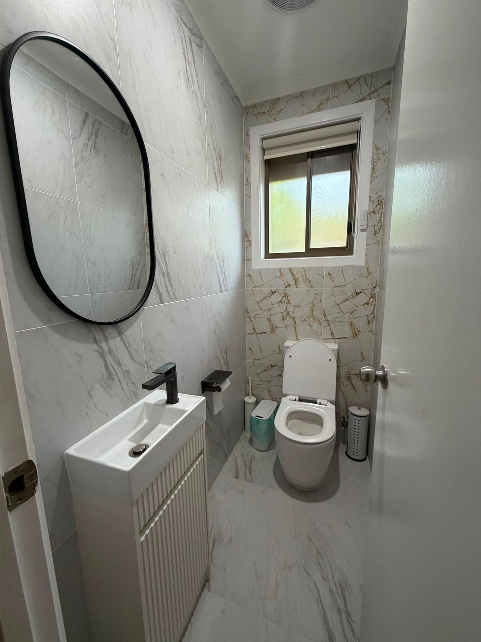 Powder room with oval mirror and fluted basin unit