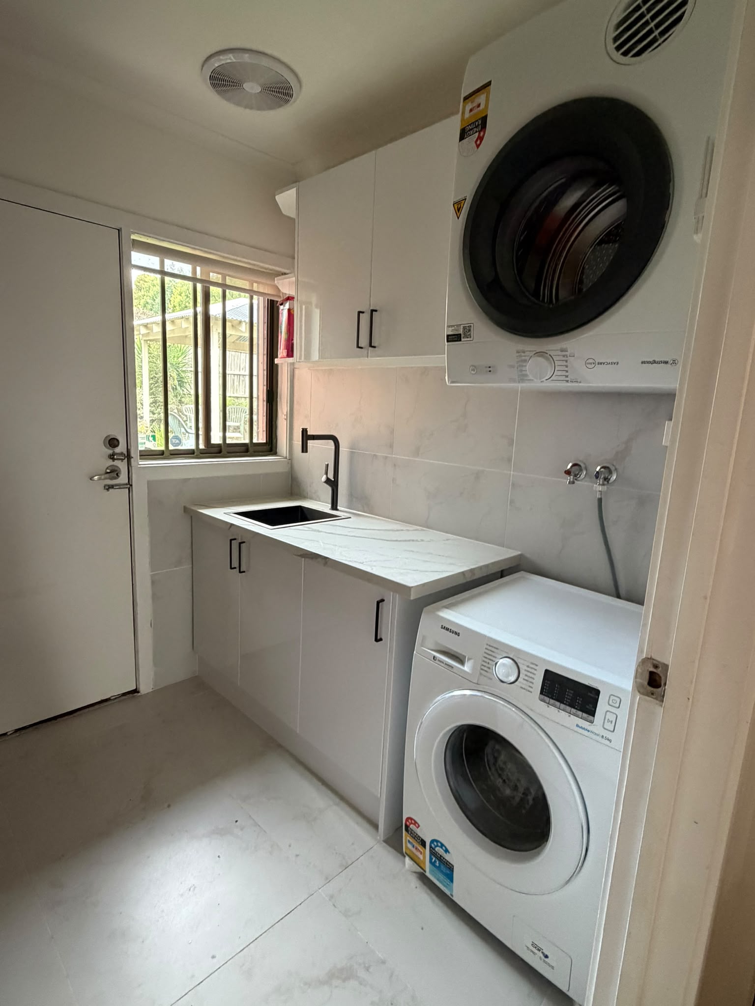 Laundry with stone bench and stacked machines